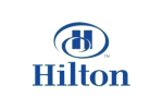 Blue Hilton logo with an oval encircling interconnected 'H' symbols and "HILTON" in bold sans-serif text, representing hospitality and global connectivity.